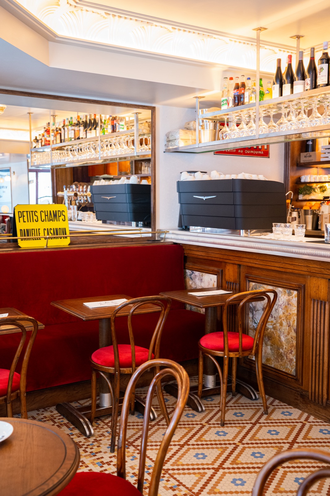La salle du Café des Moulins : bar, banquettes rouges et mosaïque